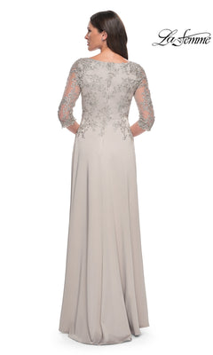 A woman faces away in a light gray lace “Long Formal Dress: La Femme 29251” with sheer embroidered sleeves and back detail.