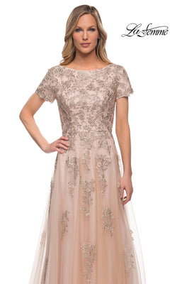 Woman in the Long Formal Dress: La Femme 29290—blush pink tulle with silver floral embroidery, short sleeves, sheer overlay—stands facing forward on a white background.