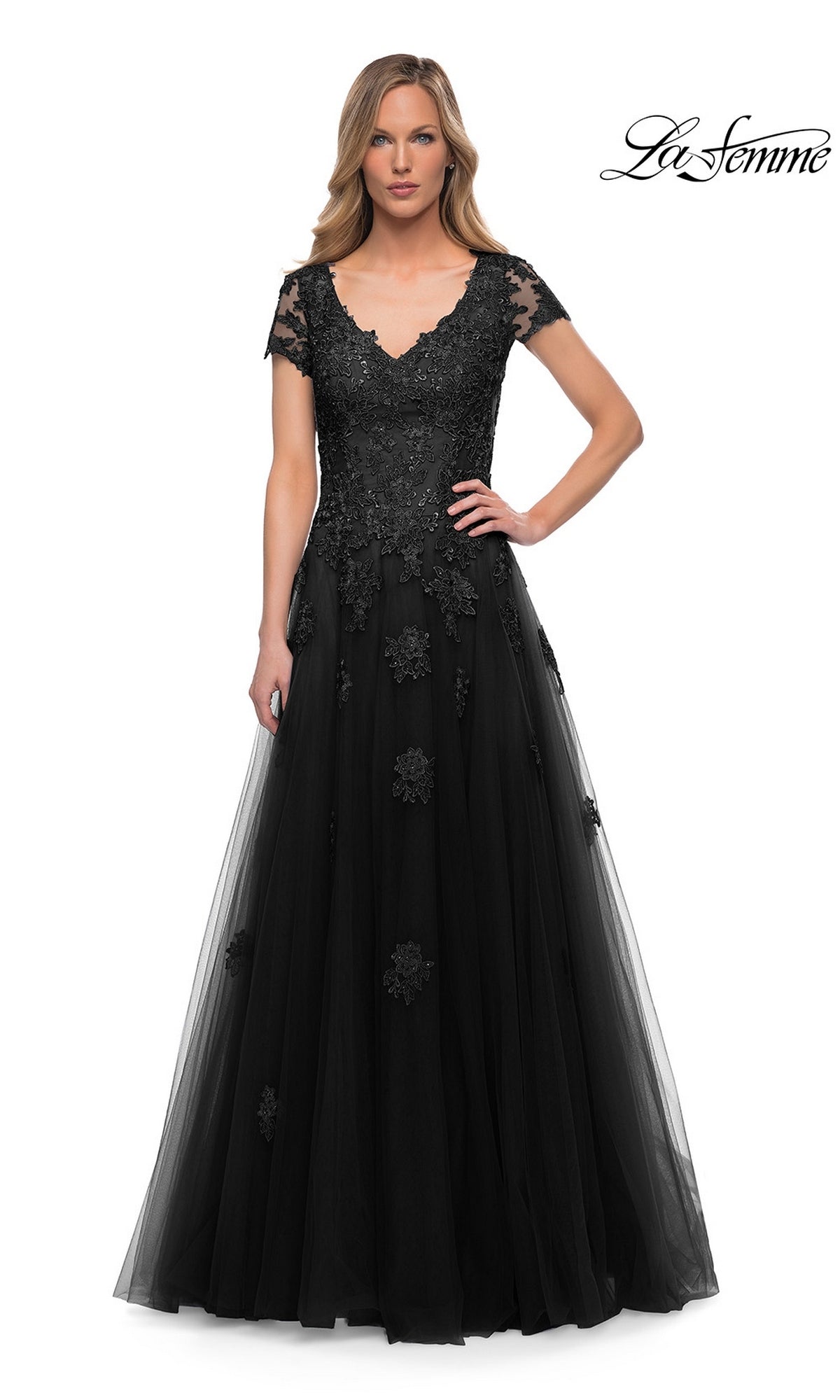 Woman wearing the Long Formal Dress: La Femme 29380 in black, featuring short sleeves, lace appliques, and an A-line tulle silhouette against a white background.