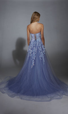 A woman wears the Strapless Glitter Prom Ball Gown: Aerie Couture 293, a strapless, floor-length blue dress with floral lace embroidery, standing with her back to a plain gray background.