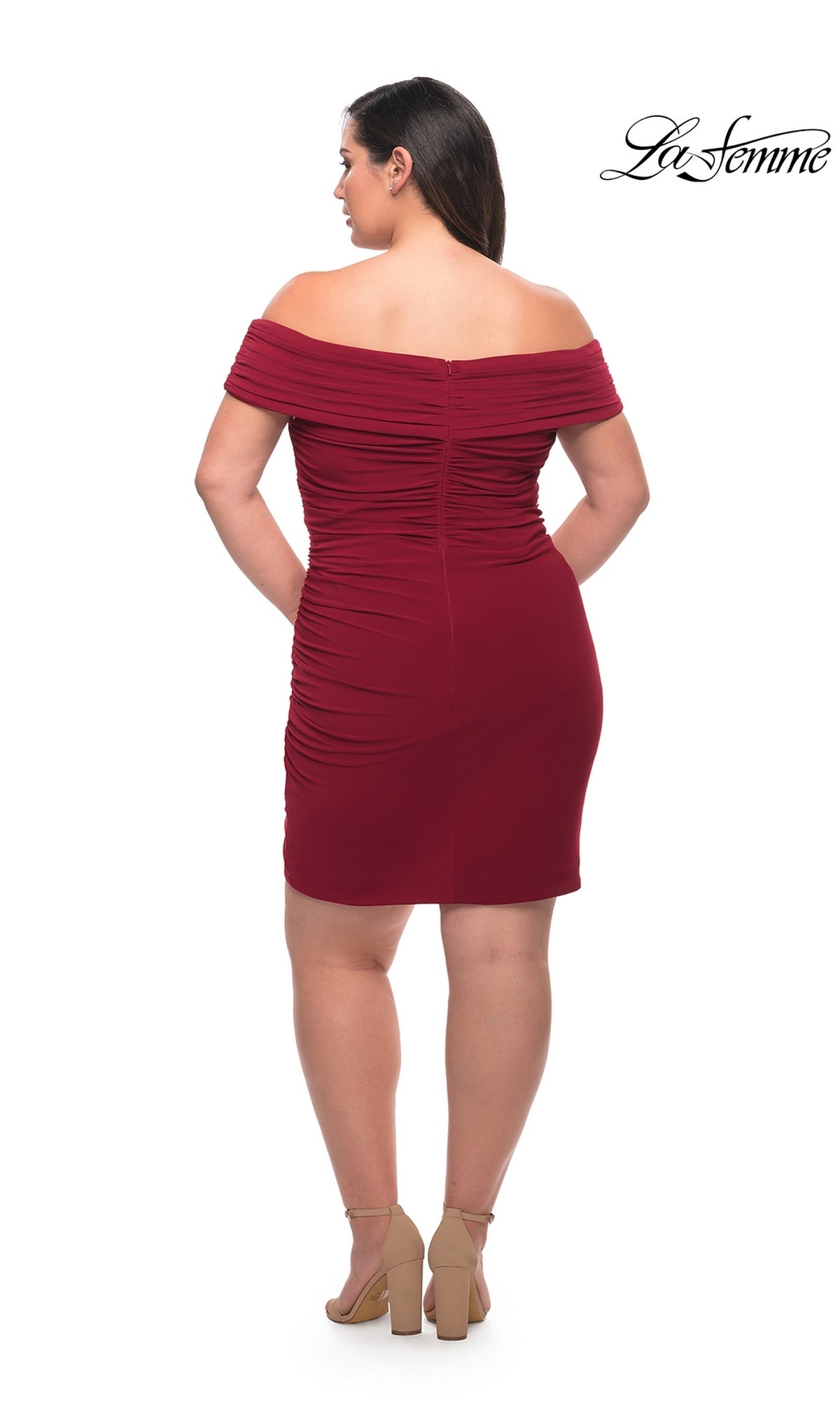 A woman models the La Femme Plus-Size Sexy Cocktail Party Dress 29521, a short off-the-shoulder dark red dress with ruching, paired with nude heels against a white background. The La Femme logo is in the top right corner.