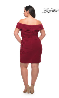 A woman models the La Femme Plus-Size Sexy Cocktail Party Dress 29521, a short off-the-shoulder dark red dress with ruching, paired with nude heels against a white background. The La Femme logo is in the top right corner.