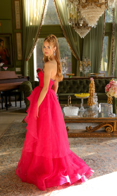 A woman in the Ava Presley 29524 strapless long prom ball gown stands in an elegant room adorned with chandeliers, large windows, and vintage furniture.