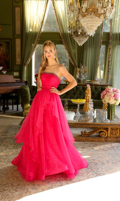 A woman in the Ava Presley 29524 Strapless Long Prom Ball Gown, bright pink and layered, stands in a luxurious room with chandeliers, flowers, and large draped windows.