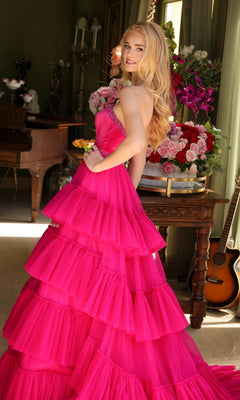 A woman with long blonde hair wears the Long Prom Dress 29529 by Ava Presley, featuring a strapless a-line design and beaded waist, posing indoors beside flower arrangements, with a guitar and piano in the background.