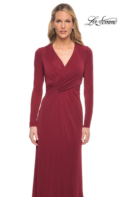 A woman wears the Long Formal Dress: La Femme 29535, a long-sleeve, deep red formal dress with a V-neckline and ruched waist detail.