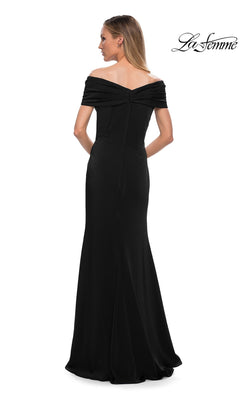A woman wearing the La Femme 29537 long formal dress, a minimalist chic, off-the-shoulder, floor-length black gown, stands with her back to the camera against a white background.