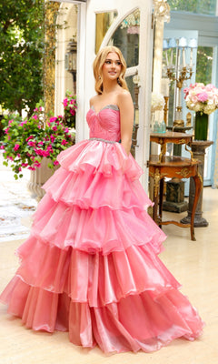 A woman in the Long Prom Dress 29546 by Ava Presley, featuring a strapless sweetheart neckline and layered ruffles, stands indoors near a window with flowers and vintage furniture.