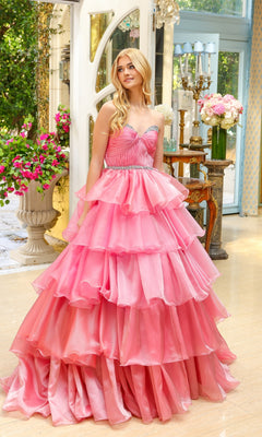 A woman wearing the Long Prom Dress 29546 by Ava Presley, featuring a layered ruffle skirt and strapless sweetheart neckline, stands indoors near a window amidst flowers and elegant decor.
