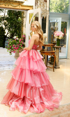 A woman wearing the Long Prom Dress 29546 by Ava Presley, featuring a strapless sweetheart neckline and layered ruffle ball gown, stands indoors by open doors with flowers and elegant furniture around her.