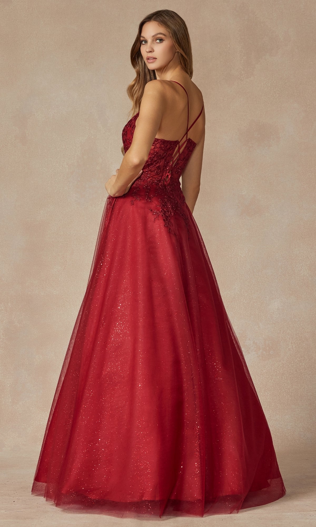 A woman poses in the Juliet 295 Lace-Up Long A-Line Prom Dress, featuring a floor-length red design with a fitted bodice, embroidered floral details, and delicate spaghetti straps against a neutral background.