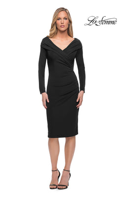 A woman models the black Knee Length Wedding Guest Dress: La Femme 29746, a knee-length, long-sleeved jersey dress featuring a V-neckline and side ruching.