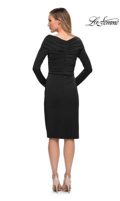 Back view of a woman wearing the Knee Length Wedding Guest Dress: La Femme 29746, a black, knee-length, fitted sheath midi dress with a ruched bodice, off-the-shoulder neckline, long sleeves, and beige heels.