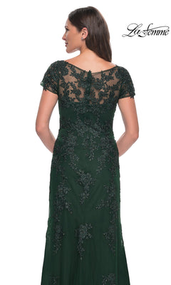 A woman seen from behind wearing the floor-length, dark green lace La Femme 29792 formal dress with short sleeves and an embroidered bodice.