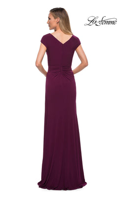 Back view of a woman wearing a floor-length, deep purple La Femme 29814 gown with cap sleeves, a gathered waist, and a cascading ruffle.