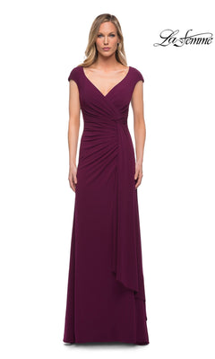 A woman wears a dark berry Long Formal Dress: La Femme 29814 featuring cap sleeves, a v-neckline, and a cascading ruffle detail gathered at the waist.