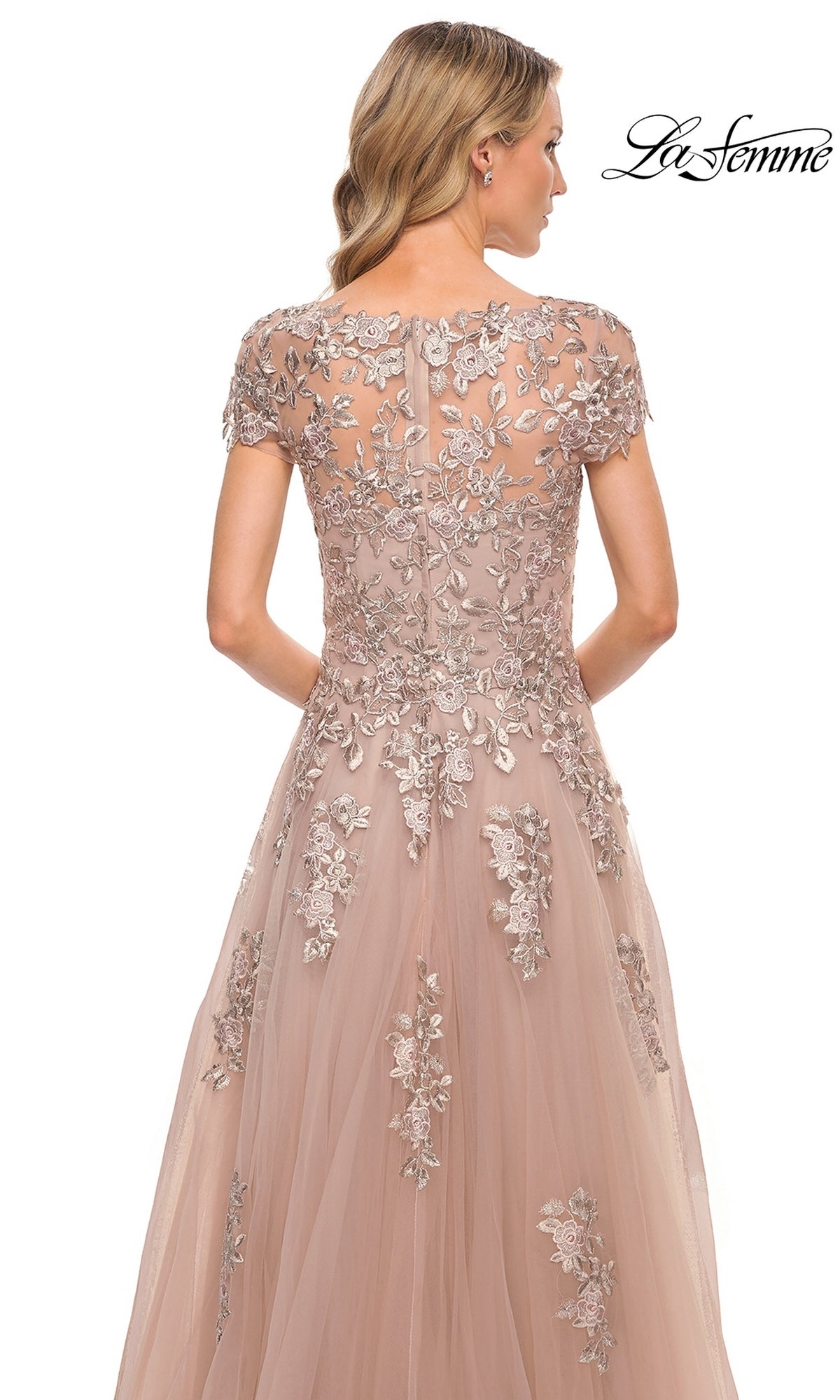 Back view of the blush La Femme 29829 formal dress, featuring a short-sleeved sheer bodice with metallic floral embroidery and lace appliques on a full skirt.