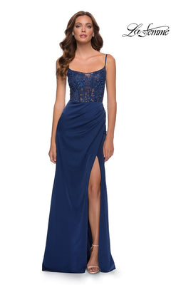 A woman wears a navy La Femme 29888 floor-length beaded lace prom dress with spaghetti straps, a satin skirt, and a high side slit.