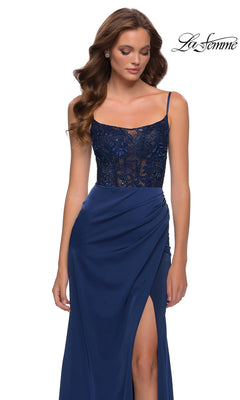 A woman wearing a Long Prom Dress: La Femme 29888, a navy blue beaded lace dress with a floor-length satin skirt, spaghetti straps, and a high leg slit.
