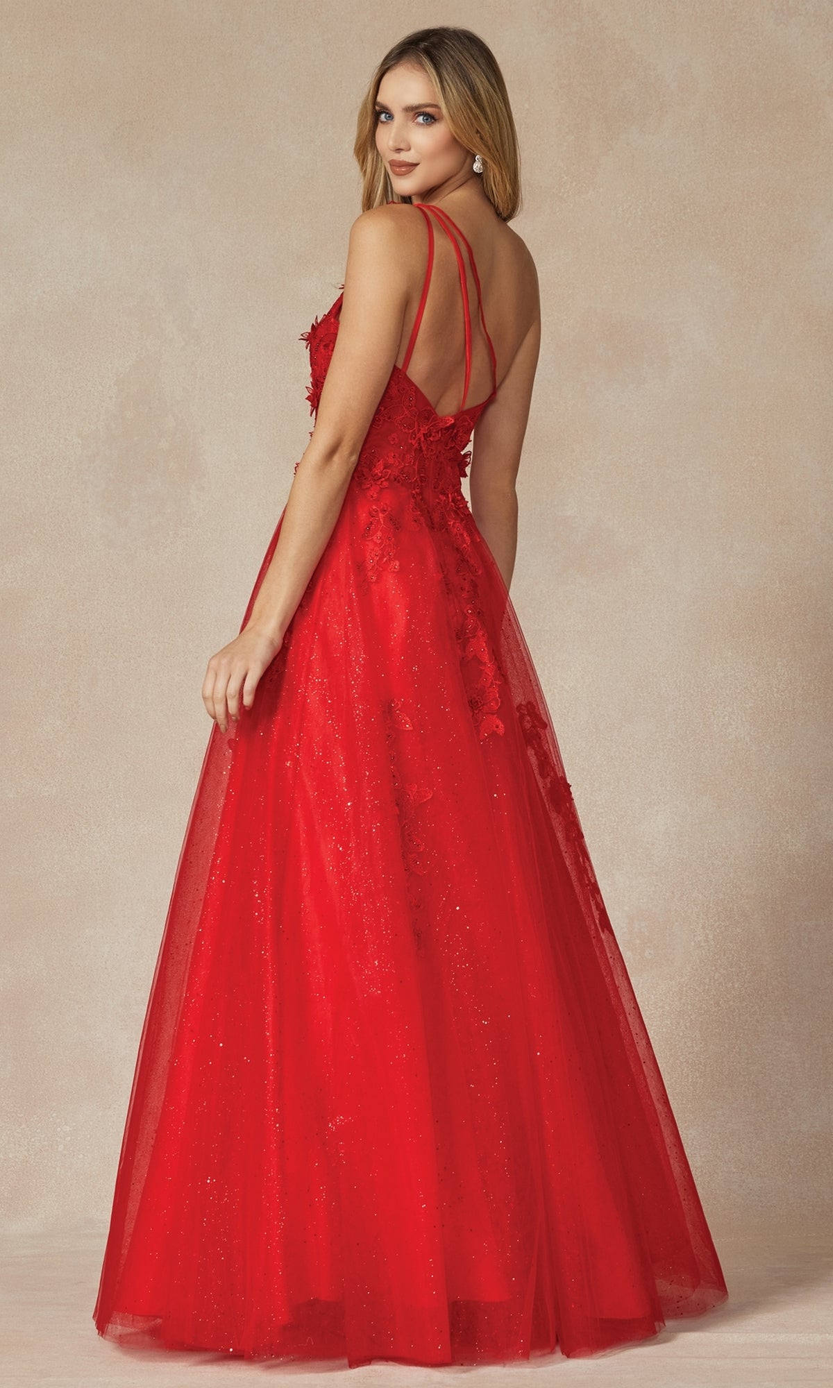 A woman in the Juliet 298 one-shoulder long red prom dress stands against a neutral background, looking over her shoulder.