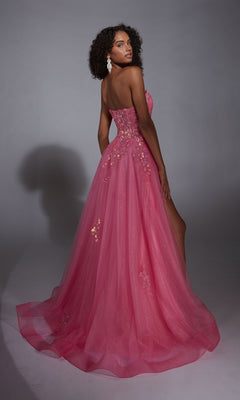 Woman in the Glitter Tulle Prom Ball Gown: Aerie Couture 298, a pink strapless dress with floral lace embroidery, stands against a plain gray background and gazes over her shoulder.