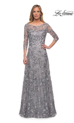 Woman in Long Formal Dress: La Femme 29903—silver, floor-length, with metallic floral lace embroidery—stands against a white background. “La Femme” logo top right.