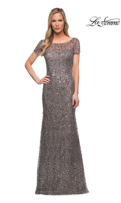 Woman in a floor-length, short-sleeve silver Long Formal Dress: La Femme 29910 with sequin details, posing against a white background. La Femme logo in upper right corner.