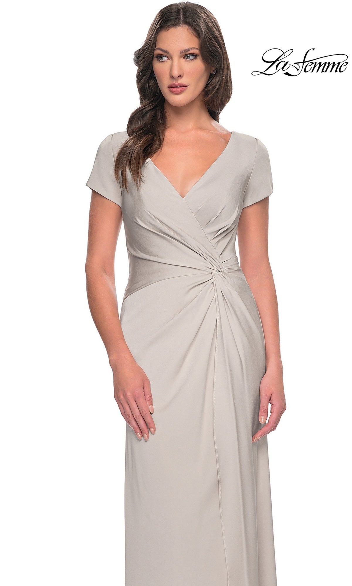 A woman wearing a light gray, short-sleeved twist-knot Long Formal Dress: La Femme 29926 with a V-neck and a gathered waist.