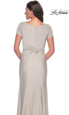 Back view of a woman in a light gray La Femme 29926 long formal dress featuring cap sleeves and a ruched, twist-knot back waist.