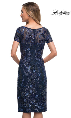 Woman wears Knee Length Mother of Bride Dress: La Femme 29959—navy, knee-length, short-sleeve floral lace with sheer upper back—facing away from the camera.