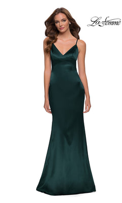 Woman in a dark emerald fitted sheath dress with thin straps, standing against a white background. “La Femme” logo appears at top right.