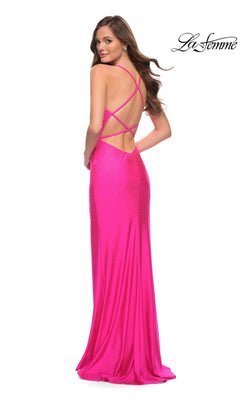 Woman wearing the La Femme Open-Back Hot Pink Long Prom Dress 29969, a neon pink, floor-length gown with crisscross straps and a backless design, standing and looking over her shoulder.