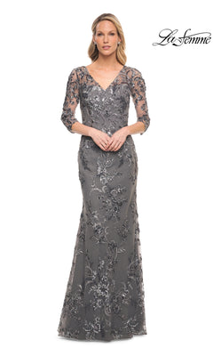 A woman wearing a Long Formal Dress: La Femme 29976, a modest, silver-grey, floor-length V-neck gown with three-quarter sleeves and silver floral embroidery.