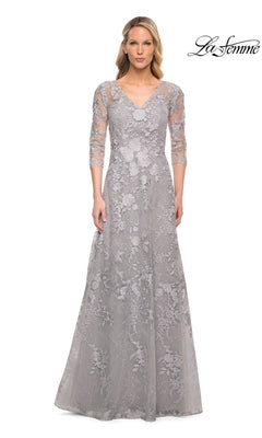 A woman wears a silver, floor-length V-neck Long Formal Dress: La Femme 29989 with three-quarter sleeves and floral lace embroidery.