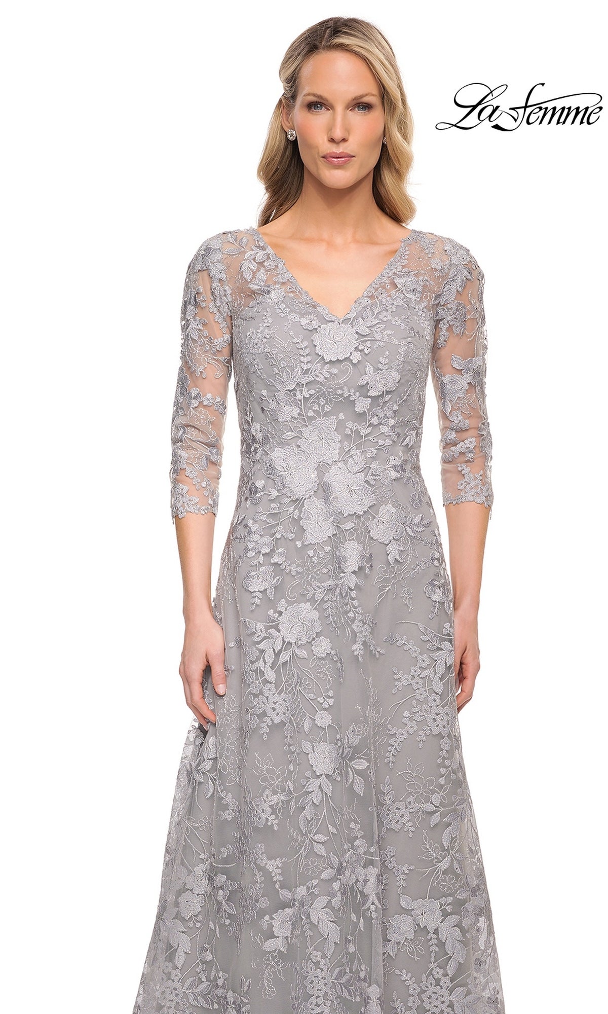 A woman wearing a La Femme 29989 long formal dress in silver with a V-neck, three-quarter sleeves, and floral embroidery.