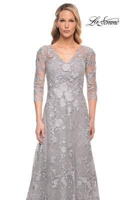 A woman wearing a La Femme 29989 long formal dress in silver with a V-neck, three-quarter sleeves, and floral embroidery.