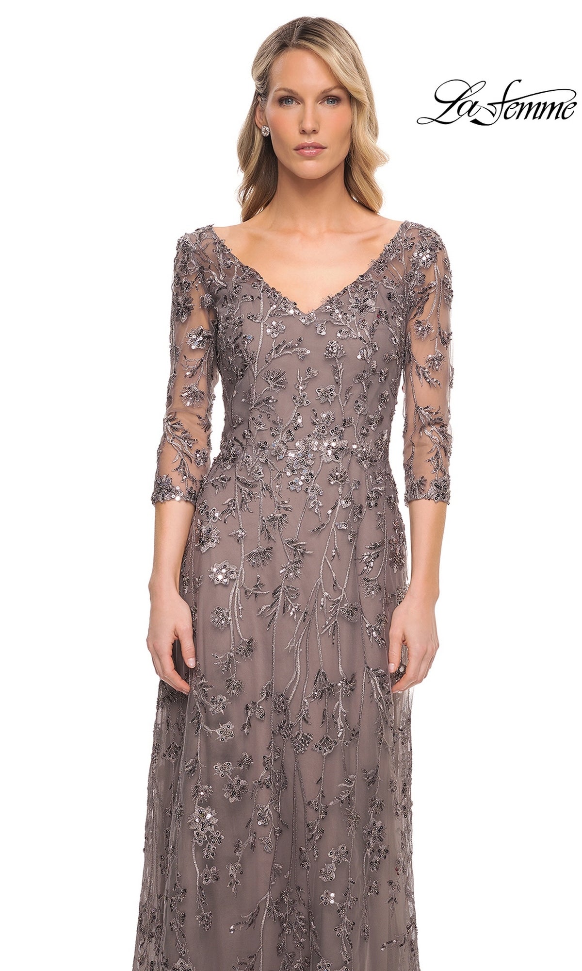 A woman wears the La Femme 29994 long formal dress, featuring a beaded V-neck, three-quarter length sheer sleeves, and tonal floral embroidery with sequins.