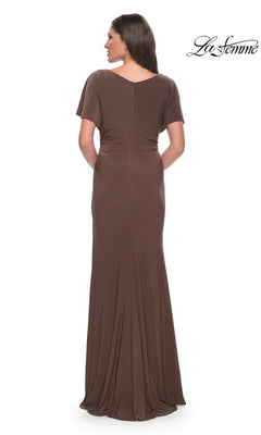 A person viewed from the back wearing a La Femme 29997, a brown V-neckline formal dress with a floor-length sheath skirt.