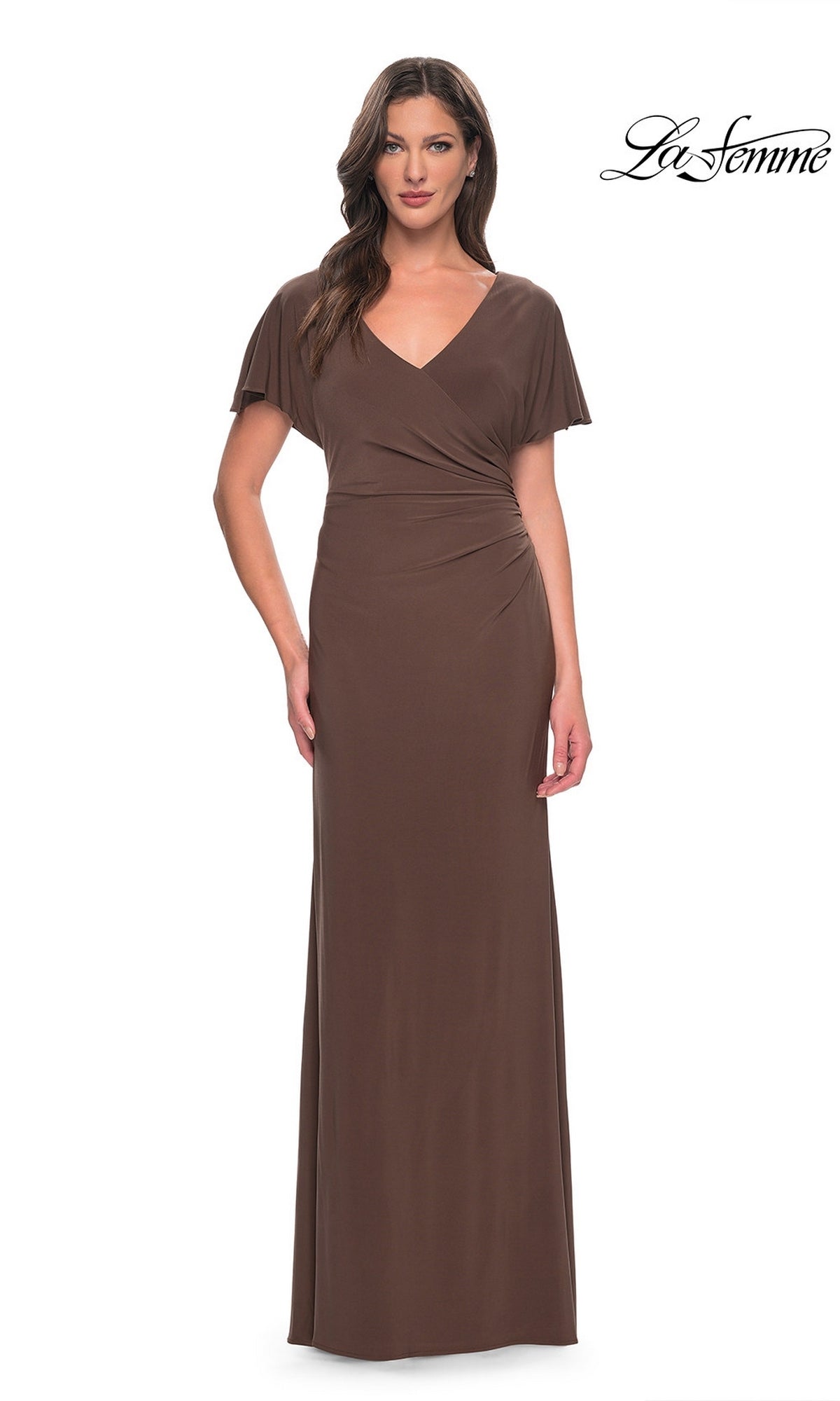 A woman wears a cocoa-colored La Femme 29997 floor-length jersey formal dress with a V-neck and flutter sleeves.