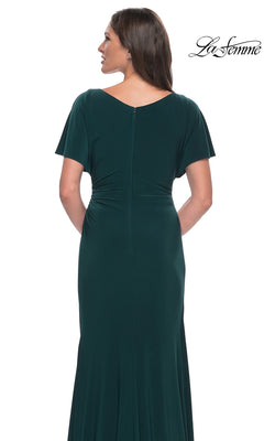 Back view of a woman wearing a dark green La Femme 29997 formal dress featuring a v-neckline, short sleeves, and a floor-length sheath skirt.