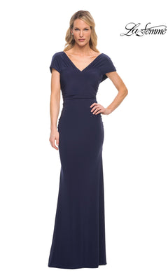 A woman wears a navy Long Formal Dress: La Femme 29998, featuring a V-neckline, cap sleeves, and a fitted sheath skirt.