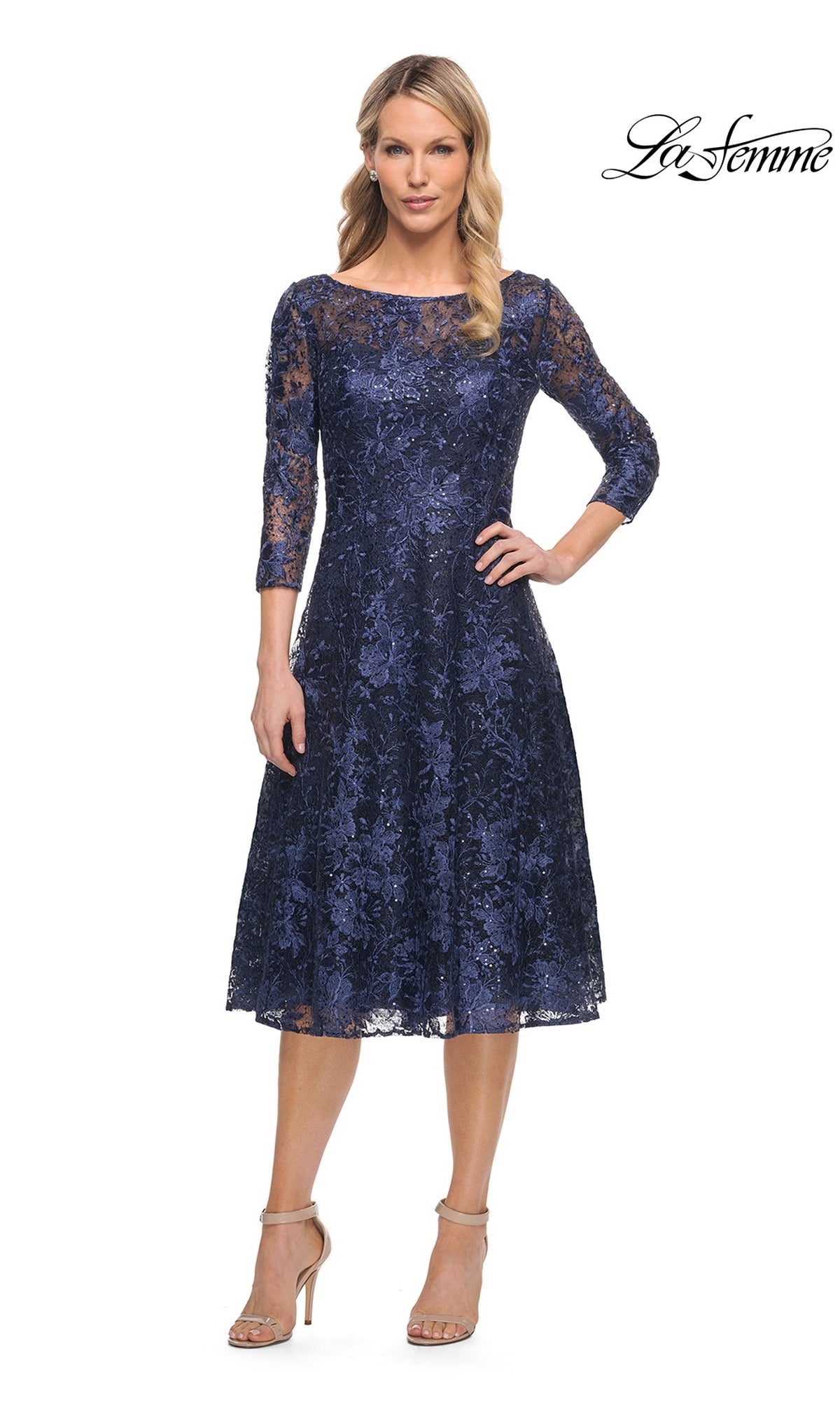 A woman wearing a navy lace Midi Wedding Guest Dress: La Femme 30005 with three-quarter sleeves, a boat neckline, and a fit-and-flare silhouette, paired with beige heeled sandals.