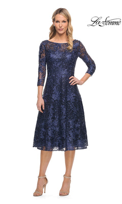 A woman wearing a navy lace Midi Wedding Guest Dress: La Femme 30005 with three-quarter sleeves, a boat neckline, and a fit-and-flare silhouette, paired with beige heeled sandals.