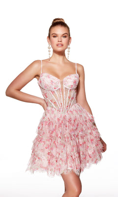 Woman in the Alyce 30009 short homecoming dress featuring pink floral print, fit-and-flare silhouette, sheer panels, tiered ruffles, and a corset bodice stands with one hand on her hip against a white background.