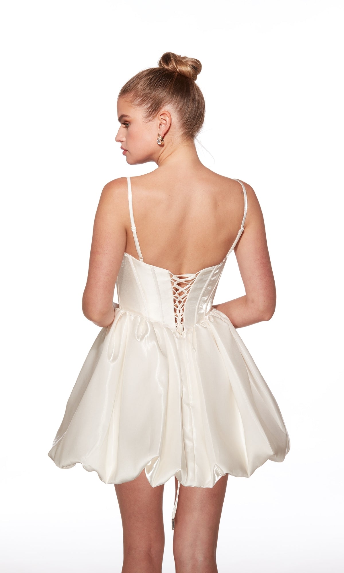 A woman with a bun hairstyle models the Bubble-Skirt Short Hoco Dress: Alyce 30012, featuring white satin, a lace-up back, and spaghetti straps, as she faces away from the camera against a white background.