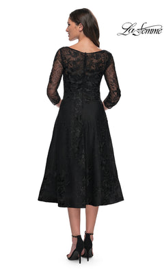Back view of a woman wearing the Midi Wedding Guest Dress: La Femme 30016, a modest lace midi dress with sheer three-quarter sleeves, floral embroidery, and black high-heeled sandals.
