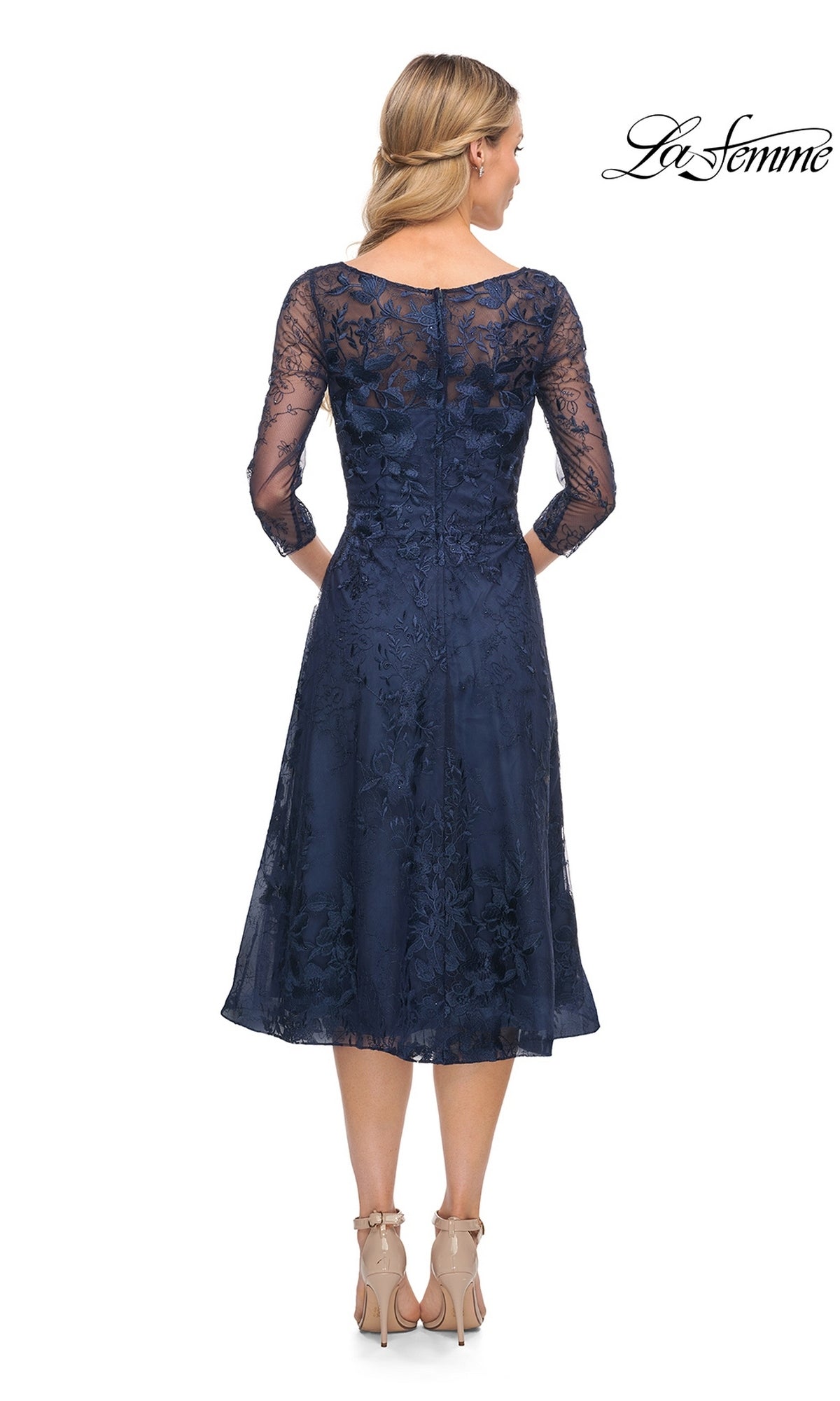 Back view of the navy blue, tea-length A-line La Femme 30016 lace dress with three-quarter sleeves and a boat neckline, worn with nude heels.