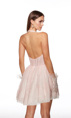 A woman poses with her back to the camera in the Alyce 30024 Short Halter Homecoming Dress, a modern take on the classic a-line party dress featuring a light pink hue, fitted bodice, and short flared skirt.