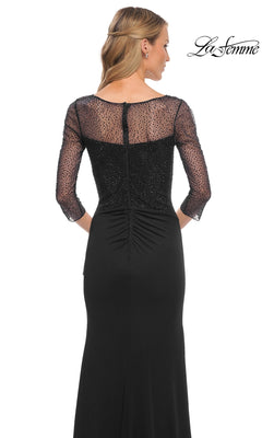 A woman wearing the Long Formal Dress: La Femme 30028 with beaded applique sleeves and sheer back stands facing away from the camera against a white background.