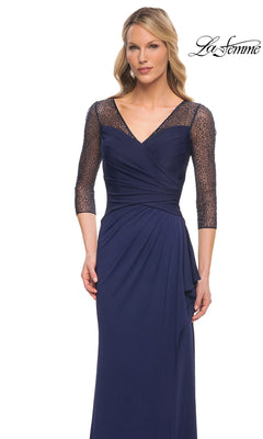 Woman wearing Long Formal Dress: La Femme 30028—navy blue jersey, V-neck, ruched waist, beaded applique sleeves. “La Femme” logo in top right corner.